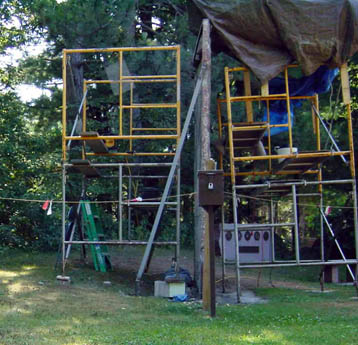 Two yellow scaffolds set up on grass among trees