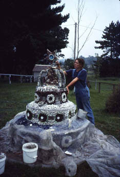 Woman in overalls beside a tiered white grotto structure with circular decorations