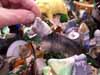 A hand reaching toward a blurry, cluttered folk-art figure and objects