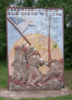 Concrete relief mural depicting figures with a pole and text