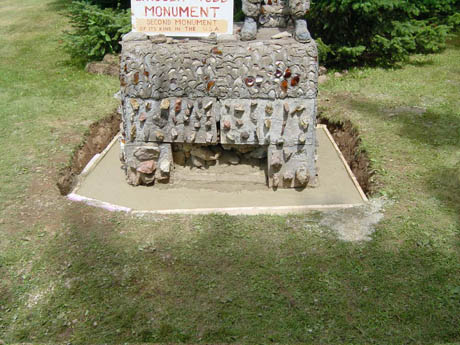 A concrete monument with a sign on top set in a grassy field