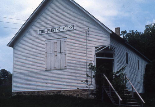 White wooden building with a sign reading The Painted Forest