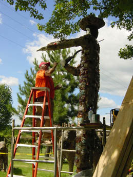 Tall textured statue being worked on by person in orange on ladder