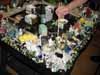 A cluttered table covered with small objects and a person's reaching arm