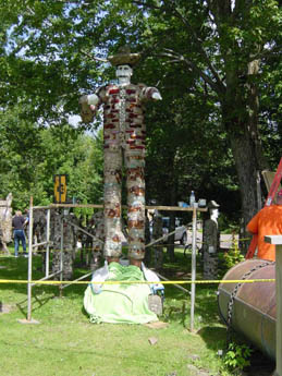 Tall mosaic-covered human figure statue with outstretched arms