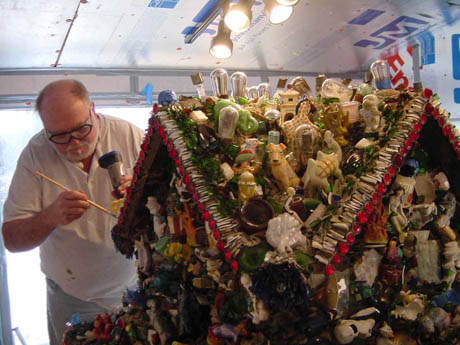 A man holding a stick beside a figurine-covered building