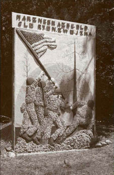 Concrete relief sculpture of soldiers with a flag beneath a sign