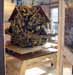 A small textured house structure on a wooden stand indoors