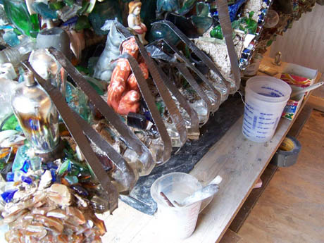 Shelf of glass bottles, jars, and rusty saw blades with plastic cups