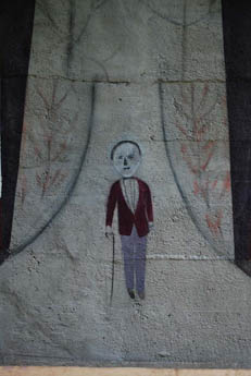 Painted mural of a man in red holding a cane on a concrete wall
