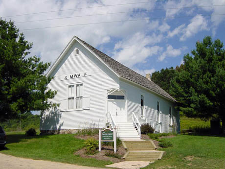 White clapboard building with gabled roof and MWA lettering