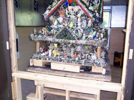 A small house densely covered in shells, beads, and trinkets