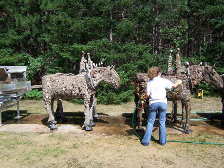 Concrete horse statues with figures on their backs and a person standing nearby