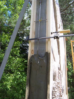 Concrete wall with embedded metal grid and wet mortar under construction