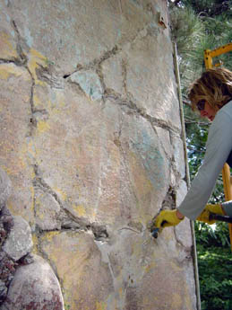 A person in yellow gloves working on a textured cracked concrete wall