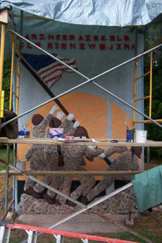 Metal scaffolding in front of a painted mural of camouflaged figures