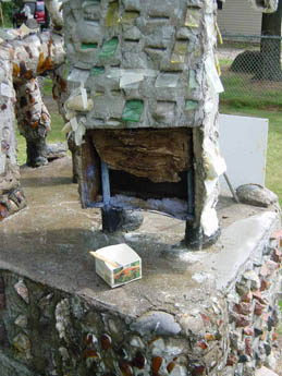 A concrete fireplace structure with an open firebox and a small box in front