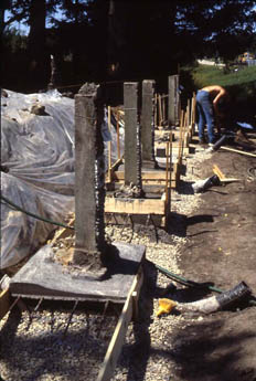 Wooden post framework and tarp at an outdoor building site with a person